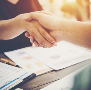 Close-up of two business people shaking hands while sitting at the working place.